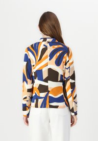 Blusa a maniche lunghe con un motivo astratto in tonalità di blu, arancione e marrone su uno sfondo beige; finitura satinata, vestibilità su misura.