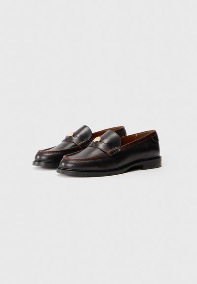 Bruna läder loafers med rund tå, stickade detaljer och en liten guldfärgad accent fram. Helt svart gummisula.