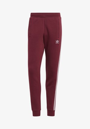 Pantalon de survêtement Adidas marron avec bandes blanches sur les côtés, taille élastique, poignets aux chevilles et poches avant, avec le logo Adidas sur la cuisse.