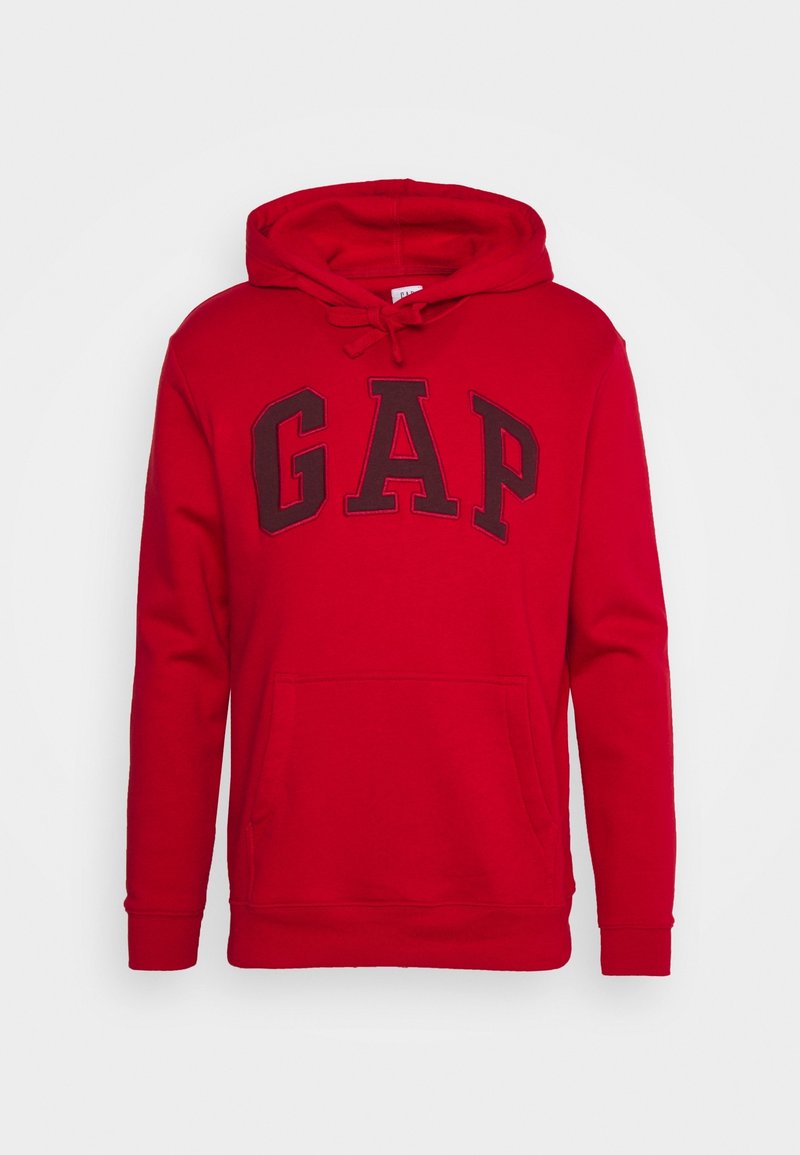 Sudadera roja fabricada con una mezcla de algodón, que presenta un gran logo negro de "GAP" en el frente, un bolsillo tipo canguro y una capucha ajustable con cordón.