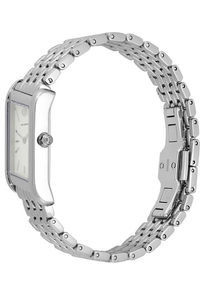 Srebrny zegarek na nadgarstek z prostokątną kopertą i białą tarczą. Posiada ogniwowy metalowy bransolet i polerowane wykończenie. Zapięcie regulowane.