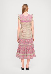 Maxikjole i lysegrønn med rosa blomster mønster, volang ermer og lagdelt nederdel. Har en innsnørt midje og detaljert rygg.