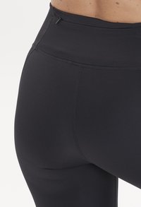 Höga svarta leggings tillverkade av stretchigt material, med en tajt passform, slät textur och en liten dragkedja i midjan.