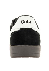 Zapatillas negras de ante con detalles en cuero blanco y suela de goma gris. Cuenta con un logo en el talón. Diseño clásico de caña baja.