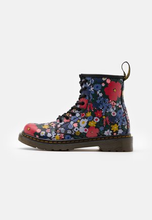 Bloemrijke vetersoldatenboot met een zwarte basis, versierd met multicolore bloemen, een gestructureerde rubberen zool en een gele lusaccent op de hiel.