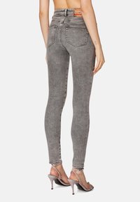 Úzké džíny ve vybledlém šedém denimu s vysokým pasem, pěti kapsami a jemnými stehmi, doplněné stříbrnými sandály na vysokém podpatku.