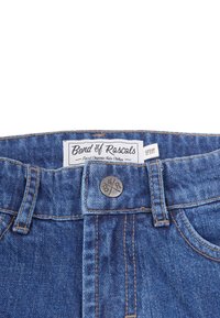 Cintura di jeans di cotone blu per bambini con bottone metallico ed etichetta con scritto "Band of Rascals, Finest Organic Kids Clothes" e taglia 110/116.