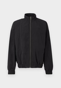 Schwarze Jacke mit hohem Kragen, Reißverschluss vorne, elastischen Bündchen und Saum. Hergestellt aus leichtem Stoff, mit einem dezenten Logo und Kontrastnähten.