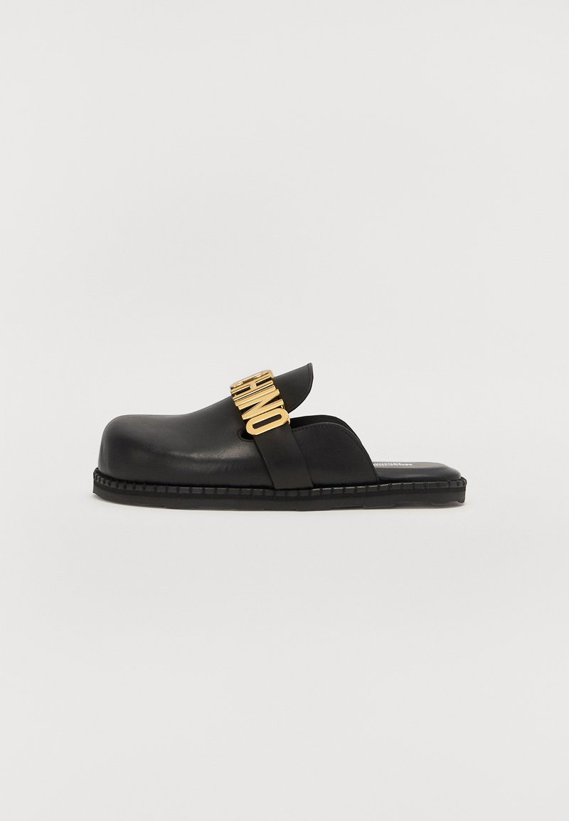 Black leather slide sandal with a wide strap featuring gold branding, rounded toe, and thick sole with detailed stitching.
