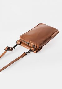 Bruine leren schoudertas met een ritsluiting, gladde textuur, verstelbare band en metalen hardware accenten. Compact rechthoekige vorm.