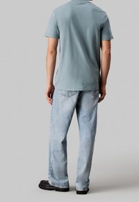 Vaaleansininen puuvillainen t-paita, jossa on lyhyet hihat ja pyöreä kaula-aukko, yhdistettynä vaaleansinisiin farkkuihin, joissa on klassinen leikkaus ja hienovarainen haalistuma.