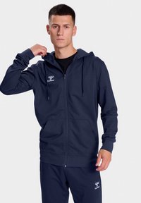 Marine blauwe rits hoodie gemaakt van zachte stof, met een kangoeroezak, verstelbare trekkoordkap en logo op de linkerborst.