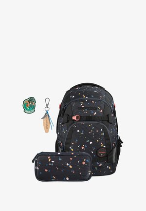 Black fabric backpack with multicolored speckled pattern, adjustable straps, front zipper compartment, tag with wooden accent, and pencil case.
