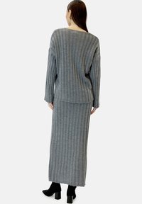 Completo in maglia a costine grigio composto da un maglione oversize e una gonna lunga abbinata, con una finitura testurizzata e dettagli sul fondo.