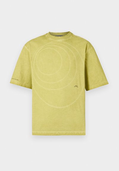 Light yellow cotton t-shirt featuring a round neckline, short sleeves, and a spiral stitch pattern on the front. Minimal branding at the bottom.