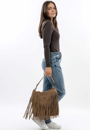 Brown suede handbag with fringe detailing, a top handle, and a single outer pocket. Worn with light blue, high-waisted jeans and white sneakers.