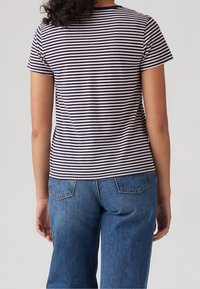 Camiseta a rayas en azul marino y blanco con mangas cortas, escote redondo, material de algodón suave, combinada con jeans de tiro alto en azul.