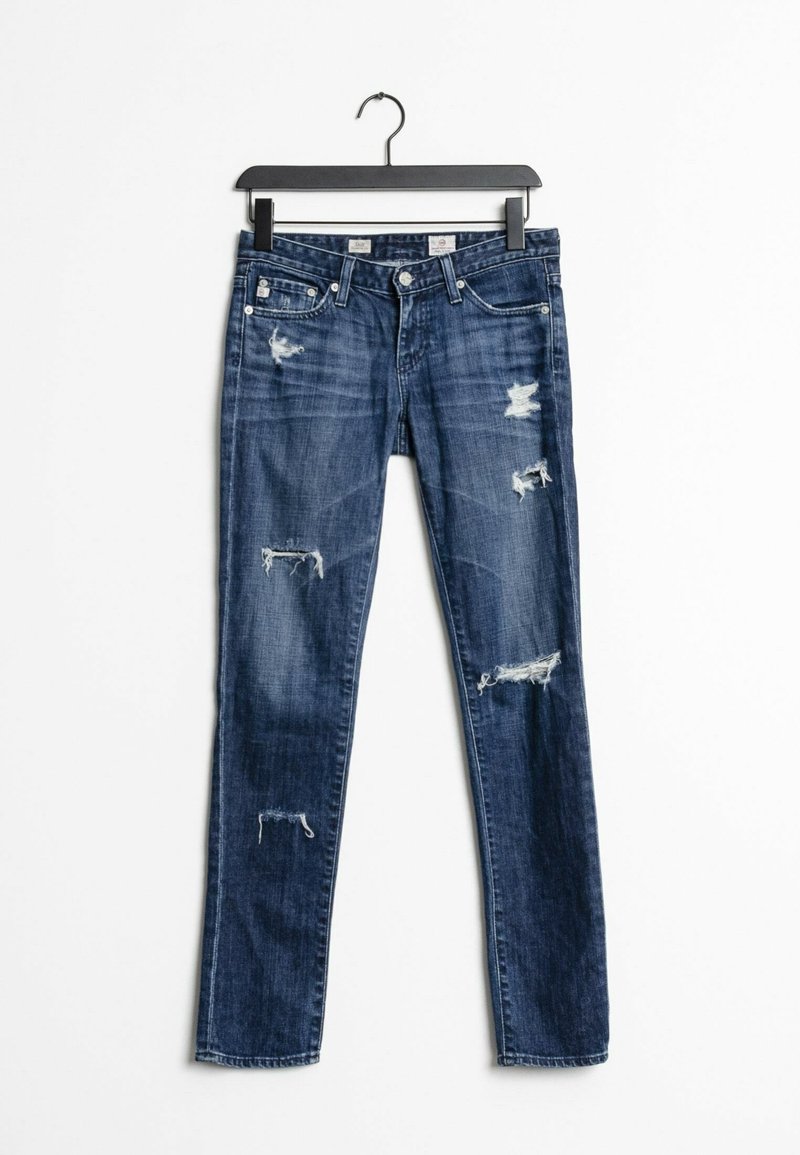 Úzké džíny v tmavě modrém denimu s opotřebovanými záplatami a třepenými okraji. Mají pět kapes a standardní pás s knoflíkovým zapínáním.