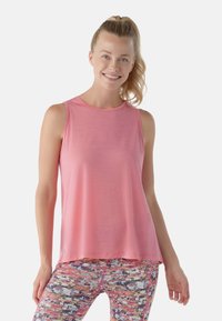 Top senza maniche di un rosa chiaro con scollatura rotonda, abbinato a leggings multicolori con motivi che presentano design e texture astratti.