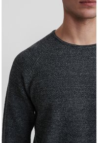 Mörkgrå texturerad tröja med rund halsringning och subtilt mönster, med en tättvunnen tyg och klassisk passform.