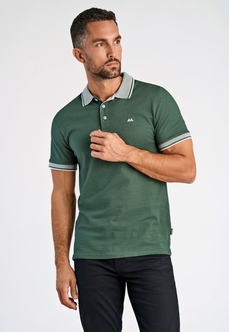 Camisa polo verde con cuello gris y acentos a rayas, fabricada con una tela texturizada, que cuenta con un cierre de tres botones y un detalle de logo.