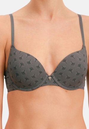 Sujetador gris con aros y patrón floral negro, con tirantes ajustables, usado en el torso superior y los hombros de una persona.