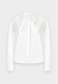 Camicia bianca a maniche lunghe con ampio colletto in pizzo a punta, dotata di ricami floreali e bottoni frontali nascosti.