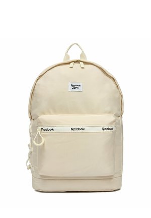 Beżowy plecak Reebok z przednią kieszenią na suwak, logo Reebok na suwaku kieszeni oraz na centralnej naszywce, z górnym uchwytem do noszenia.