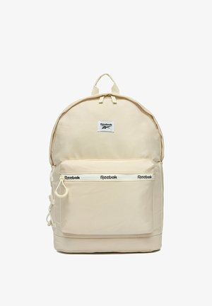 Beżowy plecak Reebok z przednią kieszenią na suwak, logo Reebok na suwaku kieszeni oraz na centralnej naszywce, z górnym uchwytem do noszenia.