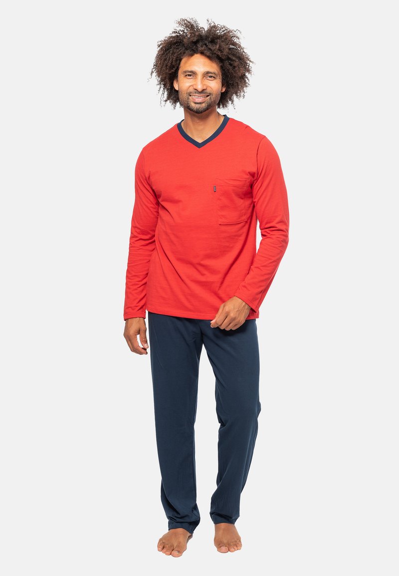 Rode langemouw V-hals shirt met een borstzak, gecombineerd met loszittende marineblauwe broek. De stof lijkt zacht met een gladde textuur.