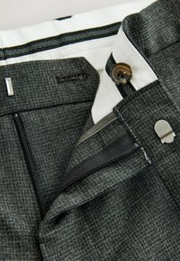 Gray textured fabric trousers with a zip fly, button closure, and striped waistband lining; features a zipped pocket and metal accents.