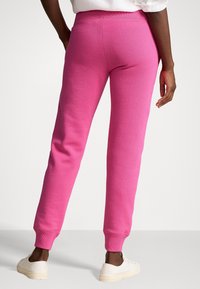 Fleecebyxor i en livlig rosa färg, med en åtsittande midja och ribbade mudd, med en slät yta och en avslappnad passform vid höfterna.