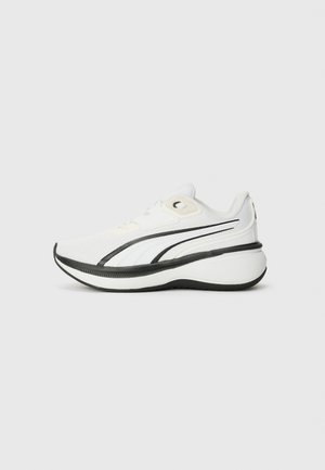 Chaussure de sport blanche avec une tige en mesh texturé, des rayures noires, une semelle arrondie et un design à lacets pour un ajustement sûr.