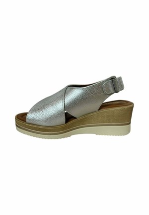 Sandalias de cuña de cuero plateado con un acabado texturizado, punta abierta, diseño de correas cruzadas y correa trasera ajustable, que presentan una suela de color claro.