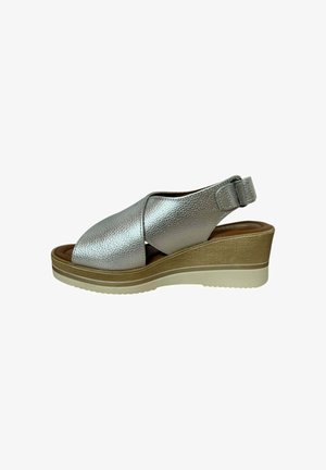Sandalias de cuña de cuero plateado con un acabado texturizado, punta abierta, diseño de correas cruzadas y correa trasera ajustable, que presentan una suela de color claro.