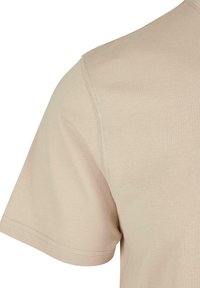 Beige T-shirt met korte mouwen, met een zachte textuur, ronde halslijn en zichtbare naden langs de schouders en zijkant.