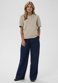 Béžová pletená polokošeľa s krátkymi rukávmi, s trojitém gombíkovým zapínaním. V kombinácii s voľnými tmavomodrými džínsami.