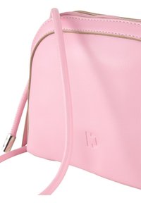 Borsa a tracolla rosa in pelle con una texture liscia, dotata di chiusura a zip, rifiniture in contrasto color tan e un logo discreto impresso sulla parte frontale.