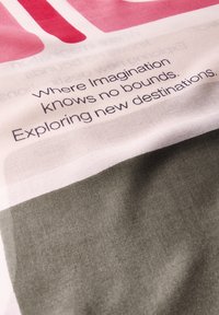 Katoen stof met gedurfde roze en groene geometrische vormen, met de tekst "Waar verbeelding geen grenzen kent. Nieuwe bestemmingen verkennen."