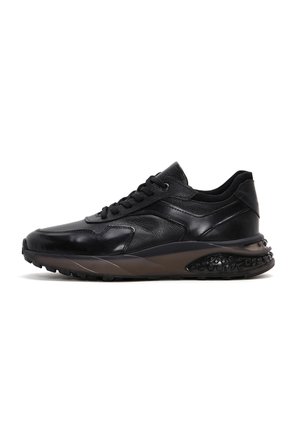 Zapatillas de cuero negro con un diseño elegante, partes superiores texturizadas, acentos perforados y una suela de goma con un patrón distintivo.