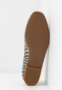 Chaussure plate avec une tige en tissu à imprimé zèbre. Elle présente une semelle en caoutchouc marron avec des motifs en vagues et un logo de marque en relief, taille 4½.