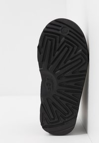 Suola di scarpa in gomma nera con motivo a zigzag. Presenta un logo centrale e una superficie testurizzata. Mostra un'orientazione verticale su uno sfondo bianco.