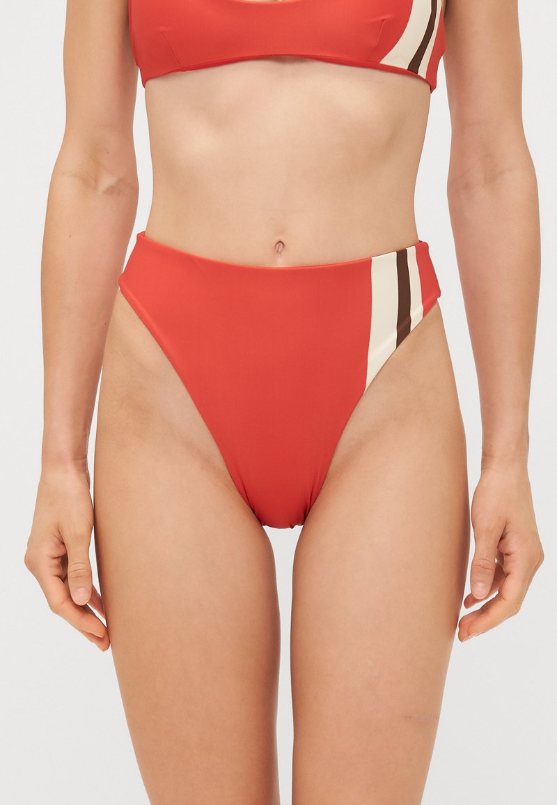 Augstās jostas sarkanā bikini apakšdaļa ar gludu tekstūru, sānos ar krēmkrāsas un brūnām vertikālām svītrām. Klasiska peldkostīmu dizaina.