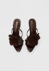Kestenjaste salonke na vezanje s patent kožom, špicastim vrhom, velikim plisiranim cvijetom od tkanine i višestrukim tankim remenčićima.