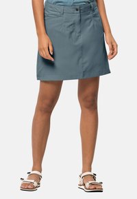 Sukně do půli kolen v odstínu modrozelené vyrobená z lehkého materiálu má zapínání na knoflík, boční kapsy a přímý spodní lem.