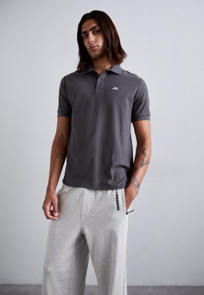 Gray polo shirt with a collar and three buttons, featuring a white logo on the left chest. Paired with light gray sweatpants with side pockets.