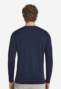 Marinblå långärmad tröja med rund halsringning. Mjuk textur, ribbade ärmslut och nederkant. Bakifrån syns en slät tygkvalitet utan synliga logotyper.