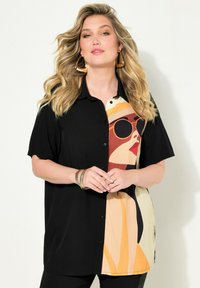 Camicia nera con bottoni caratterizzata da una grande grafica colorata di una donna che indossa occhiali da sole su un lato. Tessuto morbido con maniche corte.