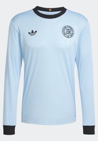 Ljusblå långärmad tröja i jersey med ribbad textur, svart krage och manschetter. Har en cirkulär svart logotyp på bröstet och en randig design.