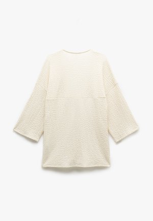 Gestructureerde crèmekleurige top met driekwart mouwen, een ronde halslijn en een losse, comfortabele pasvorm. Geen zichtbare hardware of patronen.